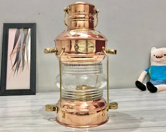 Könnte beinhalten: Eine nautische Schiffslaterne aus Kupfer und Messing mit einer Glaslinse und einem Etikett mit der Aufschrift "Leeds Burton & Sons, Outfitters for Ships".
