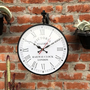 May include: Black and white clock with Roman numerals and the text "Victoria Station Railway Clock London".