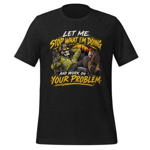 Può includere: Una t-shirt nera a maniche corte con la grafica di uno scheletro che indossa una giacca gialla ad alta visibilità, un berretto e occhiali da sole, rilassato su una sedia. Il testo recita: LET ME STOP WHAT I'M DOING AND WORK ON YOUR PROBLEM.