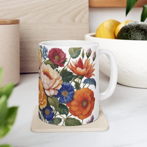 May include: White ceramic mug with a floral design featuring red, orange, yellow, blue, and green flowers. The mug has a white handle.