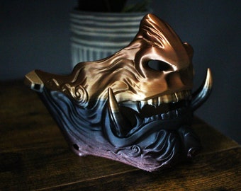 May include: A gold and black Oni mask with intricate details and a fierce expression. The mask is made of a durable material and is perfect for cosplay, Halloween, or any other occasion.
