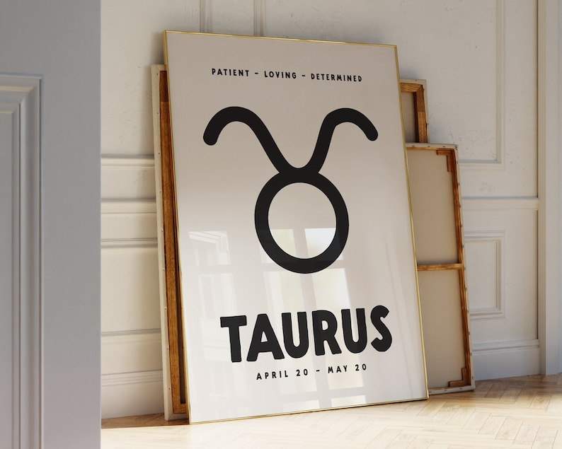 May include: A white poster with a gold frame features a black Taurus zodiac symbol and the text "PATIENT - LOVING - DETERMINED" above the symbol. The text "TAURUS" is in large, bold, black letters below the symbol. The text "APRIL 20 - MAY 20" is in smaller black letters below the word "TAURUS".