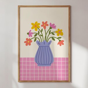 May include: A framed print of a blue vase with a bouquet of colorful flowers on a pink and white checkered background.