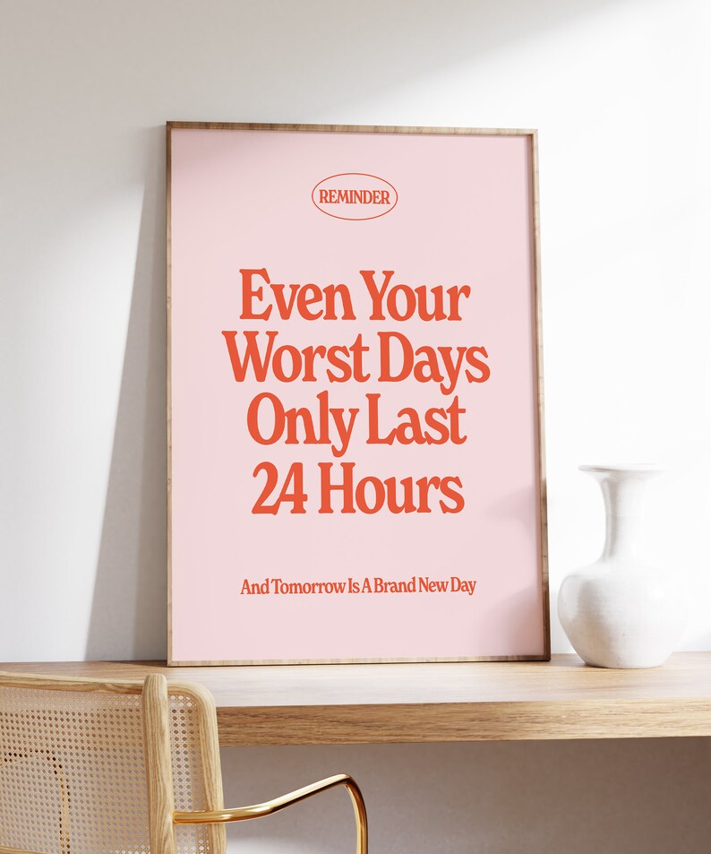 May include: A pink framed poster with the text "REMINDER" in a red circle at the top. The text "Even Your Worst Days Only Last 24 Hours" is in large red letters. The text "And Tomorrow Is A Brand New Day" is in smaller red letters below the main text.