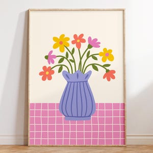 May include: A purple vase with a ruffled top holds a bouquet of colorful flowers. The flowers are yellow, orange, pink, and red. The vase is sitting on a pink and white checkered background.