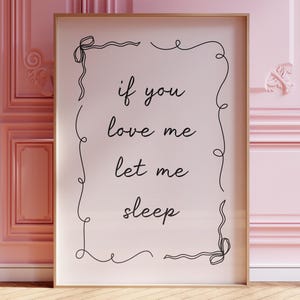 May include: A framed print with a white background and black text that reads "if you love me let me sleep". The text is surrounded by a decorative black border.