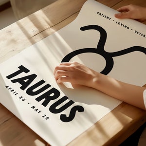 May include: A white poster with the word "Taurus" in black bold letters and the dates "April 20 - May 20" printed below. The Taurus zodiac symbol is printed in black above the word "Taurus". The text "Patient - Loving - Determined" is printed in black at the top right corner of the poster.