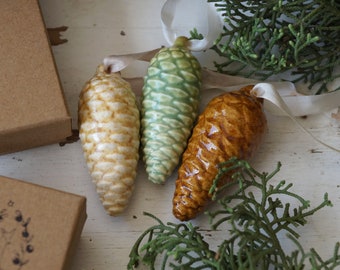 Green white and brown hanging pine cones on a Christmas tree. 3 ceramic cones of different colors and sizes. Christmas tree ornament.