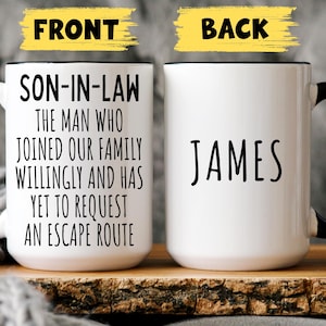May include: White ceramic mug with a black handle and rim. The front of the mug has the text "SON-IN-LAW" followed by a humorous message. The back of the mug displays the name "JAMES" in black lettering.