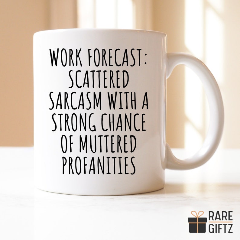 May include: White ceramic coffee mug with black text that reads "Work forecast: Scattered sarcasm with a strong chance of muttered profanities".