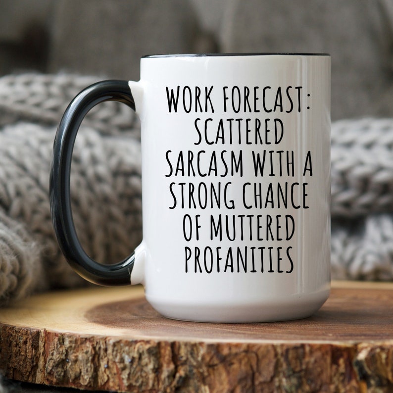 May include: White ceramic coffee mug with a black handle and black rim. The mug has black text that reads "Work forecast: Scattered sarcasm with a strong chance of muttered profanities."