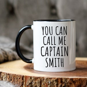 May include: White ceramic mug with a black handle and black rim. The mug has the text "You can call me Captain Smith" printed in black.