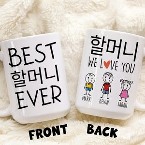 May include: White ceramic coffee mug with black text that reads "BEST 할머니 EVER" on the front and "할머니 WE LOVE YOU" with a red heart and three stick figures labeled "MARK", "KEVIN", and "SARAH" on the back.