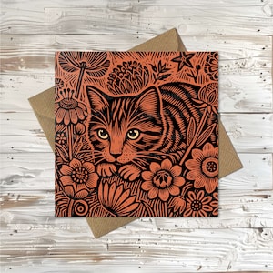 May include: A black and orange illustration of a cat with stripes, surrounded by flowers. The cat is looking directly at the viewer.