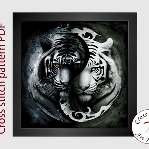 Könnte beinhalten: Ein schwarz-weißes Kreuzstichmuster mit zwei weißen Tigern, die sich in einem Yin-Yang-Symbol gegenüberstehen. Die Tiger haben blaue und gelbe Augen. Das Muster ist in einem schwarzen Rahmen gerahmt.