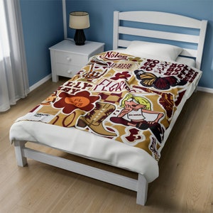 May include: A twin-sized bed with a white frame and a patterned blanket. The blanket features a collage of graphics in shades of brown, maroon, and gold, including a cowboy boot, a flower, and the text "FLORIDA".