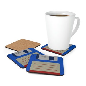 Könnte beinhalten: Vier Untersetzer mit einem blauen Disketten-Design mit dem Text "MB" auf zwei der Untersetzer. Eine weiße Keramiktasse mit Kaffee steht auf einem der Untersetzer.