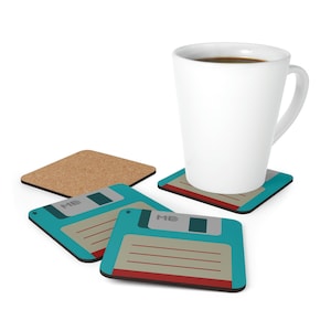 Könnte beinhalten: Vier Untersetzer mit einem Retro-Floppy-Disk-Design. Die Untersetzer sind blaugrün mit einem roten und braunen Streifen und dem Text "ME" auf jedem. Eine weiße Kaffeetasse steht auf einem der Untersetzer.