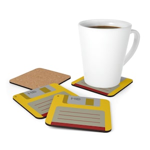 Könnte beinhalten: Vier gelbe und rote Untersetzer mit dem Text "ME" und einer Grafik einer Diskette. Eine weiße Tasse mit Kaffee steht auf einem der Untersetzer.