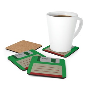 Könnte beinhalten: Vier Untersetzer mit einem grünen Disketten-Design und dem Text "ME" auf jedem. Ein Untersetzer befindet sich unter einer weißen Kaffeetasse mit Kaffee.