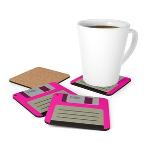 Könnte beinhalten: Vier rosa und schwarze Untersetzer mit einem Retro-Floppy-Disk-Design. Die Untersetzer tragen den Text "MB" auf der Oberseite der Diskette. Eine weiße Kaffeetasse steht auf einem der Untersetzer.