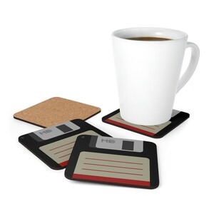 Könnte beinhalten: Vier Untersetzer mit einem Retro-Floppy-Disk-Design. Die Untersetzer sind aus Kork und haben ein Schwarz-Rot-Farbschema. Der Text "MB" ist auf den Untersetzern gedruckt. Eine weiße Kaffeetasse mit Kaffee steht auf einem der Untersetzer.