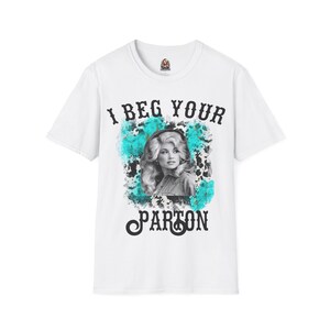 以下が含まれることがあります： 白いTシャツに、黒と白のドリー・パートンの写真と、黒い文字で「I beg your Parton」と書かれています。