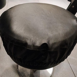 May include: Black leather seat cover for a bar stool. The cover is round and has a gathered edge.