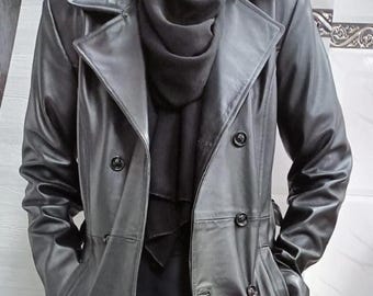 May include: A long black leather trench coat with a double breasted closure and a belt. The coat has two pockets on the front and two pockets on the sides.