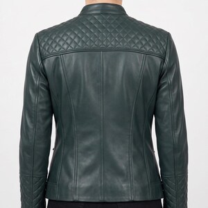 May include: A dark green jacket featuring a mandarin collar and a quilted diamond pattern across the upper back and shoulders. The long sleeves include matching quilted diamond detailing at the cuffs, with vertical seam lines along the back panel.