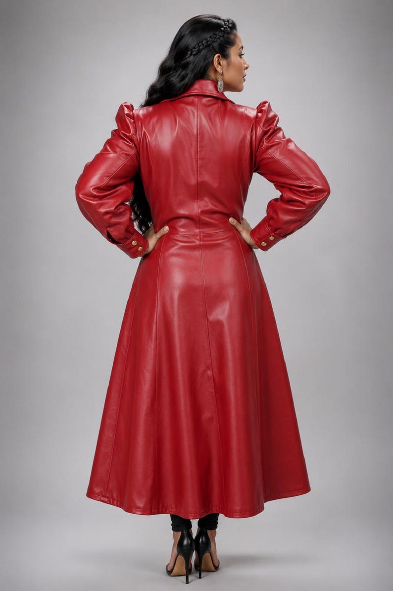 May include: A long-sleeved, floor-length red coat made of a smooth, leather-like material. The coat features a structured collar, puffed shoulders, and long sleeves with cuffs secured by gold-toned buttons. The garment has a fitted waist and a flared skirt.