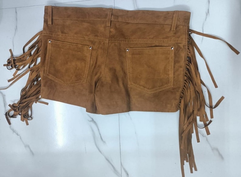 K&ouml;nnte beinhalten: Braune Wildleder-Shorts mit Fransen an den Seiten. Die Shorts haben zwei Vordertaschen und zwei Ges&auml;&szlig;taschen.