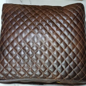 May include: A square pillow made from brown leather with a diamond quilted design.