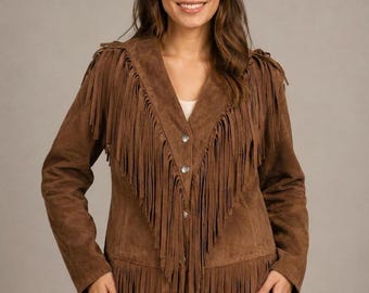 May include: A brown suede jacket featuring long fringe detailing along the front panels, shoulders, and hem. The jacket has a V-neckline, long sleeves, and is fastened with three metallic buttons down the center front, creating a textured appearance.