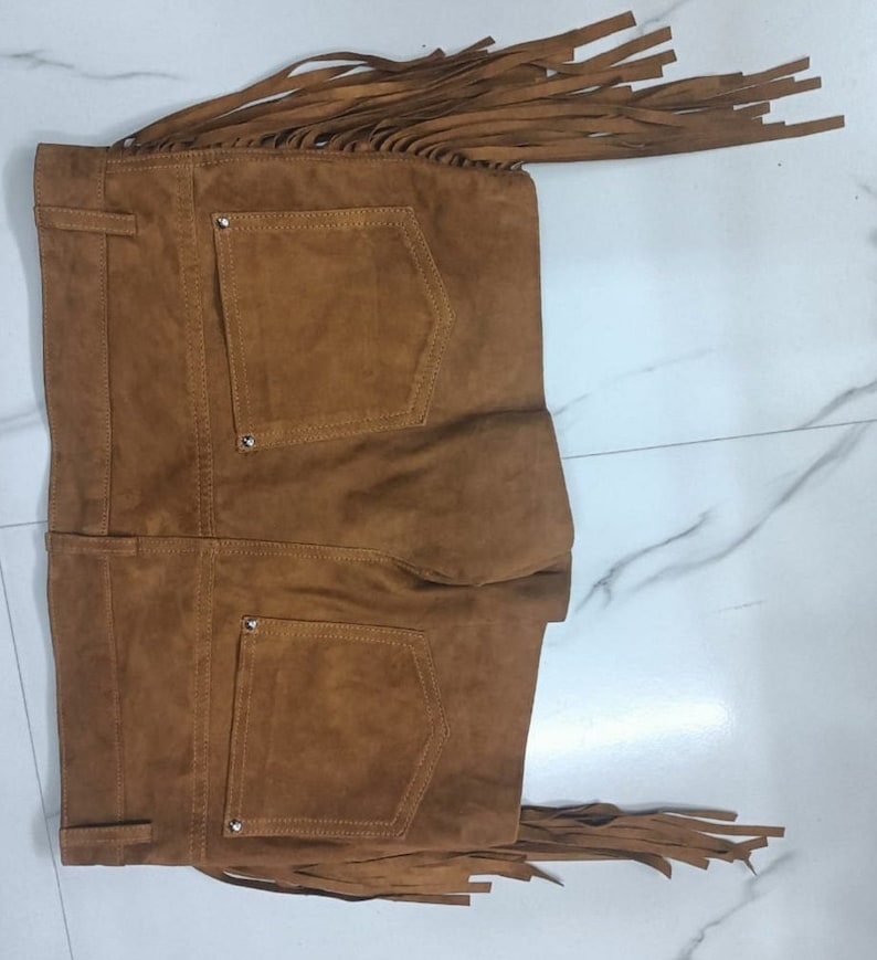 K&ouml;nnte beinhalten: Braune Wildleder-Shorts mit Fransen. Die Shorts haben zwei Ges&auml;&szlig;taschen und einen Knopfverschluss.