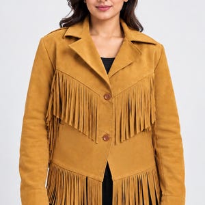 May include: A mustard yellow jacket featuring long fringe detailing across the chest and hemline. The jacket has a classic collar, long sleeves, and a two-button front closure. The material has a smooth, matte texture throughout the garment.