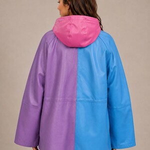 May include: A color-blocked jacket featuring a split design with a purple left side and a blue right side. The garment includes a solid pink hood, long sleeves, and a smooth finish. The jacket is shown from the back, displaying the vertical seam.