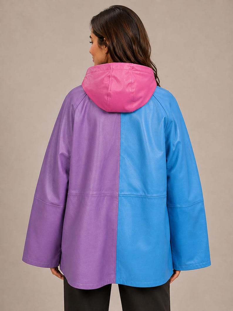 May include: A color-blocked jacket featuring a split design with a purple left side and a blue right side. The garment includes a solid pink hood, long sleeves, and a smooth finish. The jacket is shown from the back, displaying the vertical seam.