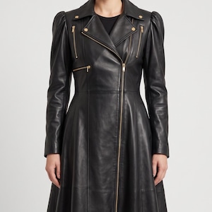 May include: A black leather coat featuring a long, flared silhouette, puff sleeves, and a notched lapel collar. The garment includes a full-length front zipper, two diagonal zippered chest pockets, and gold-toned metal hardware accents throughout.