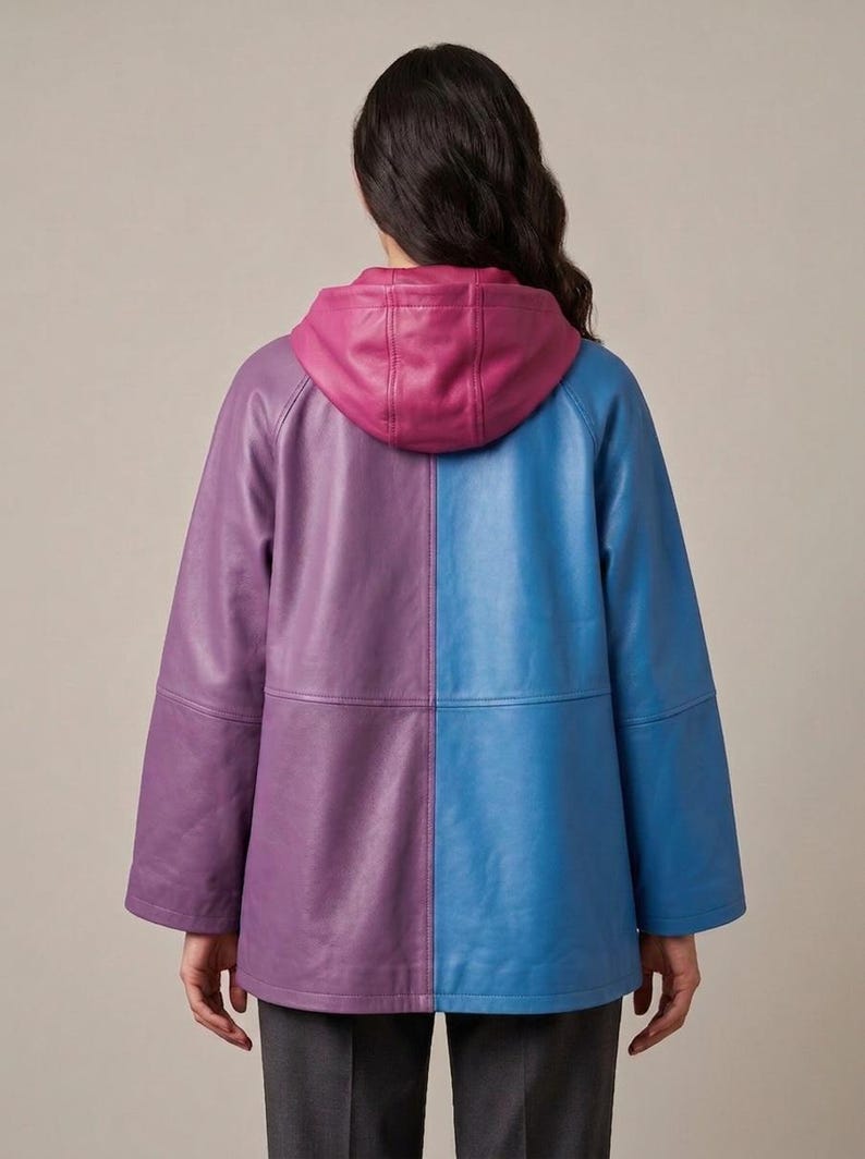 May include: A color-blocked leather jacket featuring a purple left side and a blue right side. The jacket includes a magenta hood, long sleeves, and a horizontal seam across the midsection. The design is symmetrical with a smooth finish.
