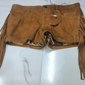 K&ouml;nnte beinhalten: Braune Wildleder-Shorts mit Fransen-Details. Die Shorts haben ein F&uuml;nf-Taschen-Design und einen Knopf- und Rei&szlig;verschluss.
