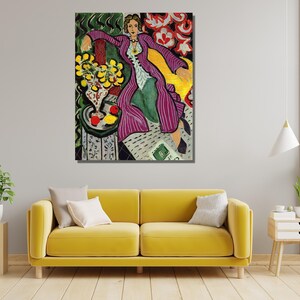 May include: A painting of a woman in a purple and white striped robe sitting in a yellow chair. The woman is wearing a gold necklace and has her hair pulled back. There are yellow lemons and red apples in a vase on a table in the background.