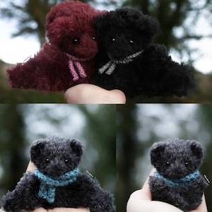 以下が含まれることがあります： スカーフを巻いた小さなテディベアが3匹います。1匹はボルドー、1匹は黒、もう1匹はグレーです。