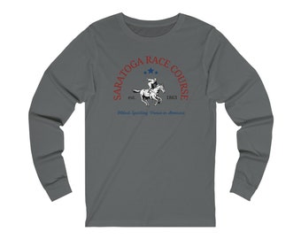Puede incluir: Una camiseta gris de manga larga con un logotipo rojo y azul que dice "Saratoga Race Course est. 1863" y "Oldest Sporting Venue in America". El logotipo presenta un jinete montando un caballo.