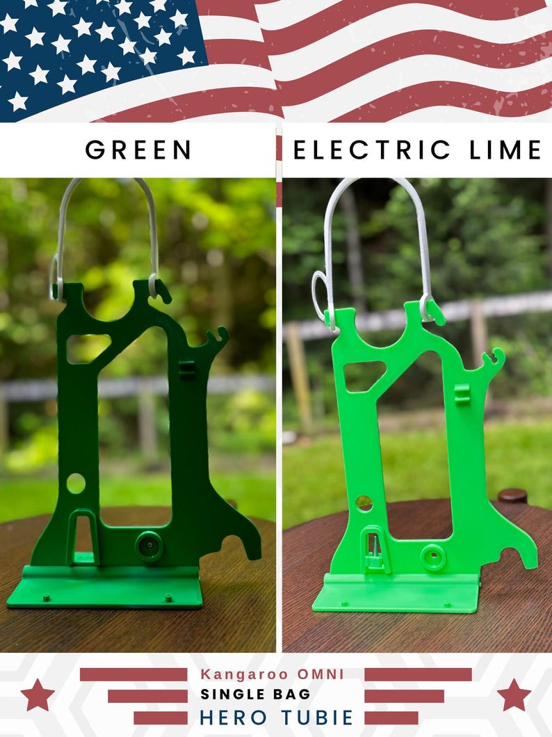 Side-by-side comparison of two Hero Tubie™ pump stands for the Kangaroo™ Omni, shown under an American flag-themed banner. The left stand is a darker “Green” color, while the right is a bright “Electric Lime.” Both stands are lightweight, 3D-printed plastic designs with a detachable white hanger for hanging a single feeding bag. They are displayed on wooden surfaces outdoors with blurred greenery in the background. Text at the bottom reads “Kangaroo OMNI Single Bag Hero Tubie.”