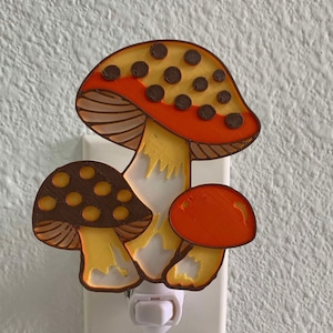 May include: A nightlight shaped like three mushrooms with brown and orange caps and yellow stems. The nightlight plugs into a standard electrical outlet.