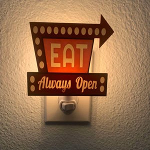 May include: A retro-style night light with a brown and orange sign that reads "EAT Always Open." The sign has an arrow pointing right and is illuminated by a soft glow. The night light is plugged into a white wall outlet.