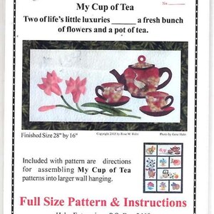 May include: A craft pattern titled Lilies TeaPot My Cup of Tea featuring a rectangular image of a red teapot and two teacups with pink lily flowers. The pattern includes instructions for a wall hanging with a finished size of 28 inches by 16 inches.