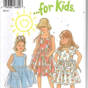 May include: A sewing pattern for children's dresses from New Look. The pattern features illustrations of three girls wearing different dress designs. The dresses include a blue dress, a patchwork dress, and a floral dress. The text "...for Kids" is in green.