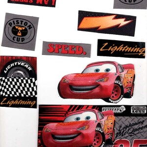 May include: A sticker sheet featuring Lightning McQueen from the movie Cars, including various decals with the text Lightning McQueen, Piston Cup, I AM SPEED, and SPEED. A wooden ruler at the bottom shows a length of approximately 5.5 inches.